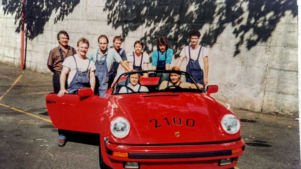 Historisches Foto: Werksteam mit einem roten Porsche Speedster, auf der Haube die Zahl 2100